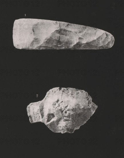 Polished ax and arrowhead of flint, page, photomechanical print, inscription: 'PL.76', monogram: 'EL', inscription: '1, 1 nature', inscription: '1. HACHE POLIE EN SILEX 2. POINTE EN SILEX', inscription: 'Procédé spécial photo-lithographique', photographer: Ville de Paris (possibly), cliché maker: Adolphe Bilordeaux (possibly), supervision: Ernest Lacan, c. 1864 - in or before 1869, printer (person), paper, photolithography, height 239 mm x width 190 mm, tools, aids, implements, crafts and industries: ax, A dark background with two grayscale stone-like objects positioned vertically, the upper object elongated with a smooth rounded right end and textured surface variations, and the lower object irregularly shaped with rough edges and surface markings.