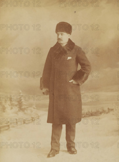 Portrait of Mr. Birks, cabinet photograph, photographer: William Notman, 1880 - 1895, paper, albumen print, height 165 mm x width 105 mm, A sepia-toned photograph of a man standing in a snowy landscape wearing a long dark overcoat with a fur collar and fur-trimmed cuffs, a round fur hat, trousers, and polished shoes; he has a mustache and a hand tucked into a pocket while the other hand hangs by his side, and snow-covered trees and a low fence are visible in the background beneath a cloudy sky.