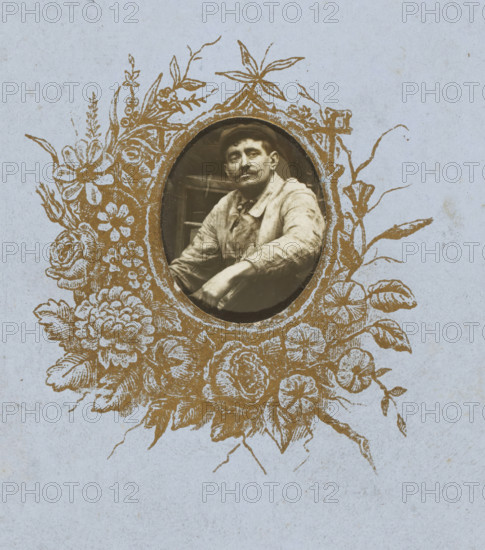 Portrait of a man surrounded by a printed representation of flowers, carte-de-visite, name: 'A. Barrès, Phot., 19, Rue Richelieu', number: '54', photographer: Alphonse Barrès, c. 1860 - c. 1890, paper, ferrotyping, ferrotype, height 106 mm x width 63 mm, An oval sepia photograph of a man with a mustache wearing a cap and light-colored clothing sits centered within an ornate gold floral frame printed on pale blue paper; the frame features stylized flowers, leaves, and vines surrounding the oval, and the man is shown from the torso up with one arm resting forward.