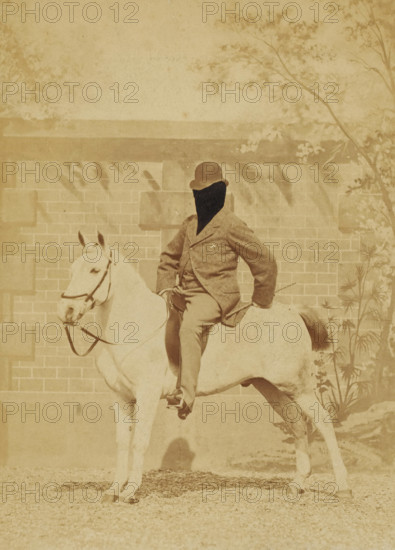 Man on horseback with his face retouched, photograph, United States of America, c. 1880 - c. 1910, photographer, North America, paper, pasteboard, albumen print, albumen print on cardboard, height 140 mm x width 102 mm, height 157 mm x width 119 mm, horse, A sepia-toned photograph of a person seated on a light-colored horse in front of a brick wall with a horizontal ledge and some foliage at the top and right side; the person wears a bowler-style hat and a textured jacket with trousers and has one hand resting on the horse's back while the other holds the reins, and the horse wears a bridle and stands with its head turned slightly toward the left side of the image.