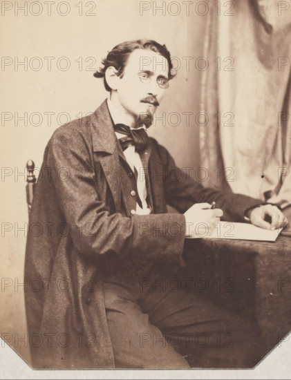 Portrait of possibly an architect, drawing with pencil in his hand, photograph, photographer: attributed to Franz Hanfstaengl, Germany, c. 1855 - c. 1860, Attributed to, pasteboard, paper, salted paper print, salt print pasted on cardboard, height 183 mm x width 142 mm, height 0 mm x width 0 mm, A seated man wearing a dark overcoat and suit jacket layered over a vest and shirt looks toward the camera while holding a pen above a sheet of paper on a table, his hair swept back, a small mustache and pointed goatee framing his mouth, round eyeglasses perched on his nose, a bow tied at his collar, a wooden chair back visible behind him and a draped curtain in the background.