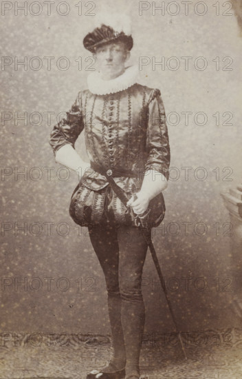 Portrait of a young man in costume with a sword, identified as CA Bergsma, album page, photograph, carte-de-visite, This photo is part of an album., name: 'CA Bergsma., 99.', inscription: 'J. Goedeljee, Photographer, HRH PRINCE ALEXANDER, of the Netherlands, PRINCE of ORANGE, and HRH, PRINCESS HENDRIK, Hoogewoerd 160, near the Plantage.', photographer: Jan Goedeljee, Leiden, 1860 - 1905, paper, pasteboard, albumen print, height 83 mm x width 52 mm, historical persons, historical costume, hacking and thrusting weapons: rapier, A sepia-toned portrait of a person standing full-length against a mottled backdrop, wearing a dark, shiny doublet with vertical decorative trim, a pleated white ruff collar, and puffed breeches; the person has a dark, pleated cap on their head, one hand resting on their hip and the other holding the hilt of a sword that extends down toward the floor, with fitted dark hose and shoes visible at the bottom.