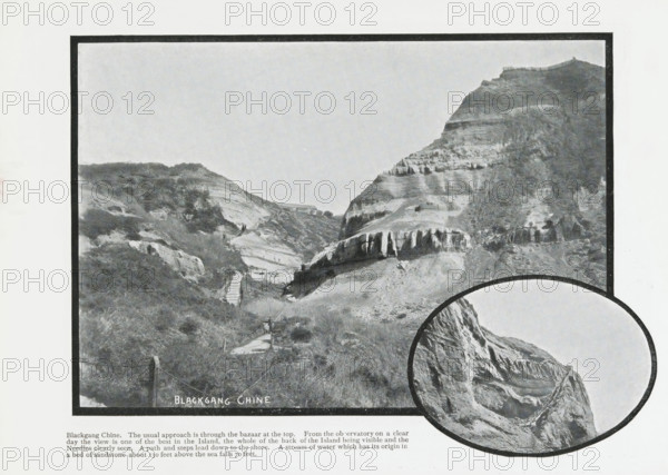 Blackgang Chine, photograph, page, Page 20 with 2 photos of Blackgang Chine and a caption. Part of Photographic travelogue of the Isle of Wight., photographer: Welch & Sons, J., Isle of Wight, in or after 1897 - c. 1930, printer (person), paper, printing, autotype, page with photos and printed text, height 169 mm x width 228 mm, travelling, tourism, ravine, chasm, abyss, canyon, inland cliff face (landscape with figures, staffage), Blackgang, A black and white framed photograph of a coastal valley with layered rock cliffs and steep slopes, showing a narrow winding path and a series of steps descending through grassy and scrubby terrain, scattered vegetation on the hillside, a small structure visible near the middle distance between the cliffs, striated rock formations and ledges on the larger cliff to the right, and an overlapping circular inset at the lower right showing a close-up of a rugged cliff face with a path or railing along its edge.