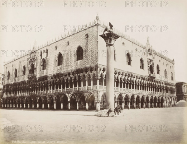View of the Doge's Palace and a pillar with a lion statue in Venice, Palais des Doges de Venise, Venezia - Palazzo Ducale veduta generale, photograph, Part of Topographical album of Venice 1881., negative number: '263', check stamp: 'Carlo Ponti Venezia', photographer: Carlo Ponti, Venice, 1860 - 1881, Carlo Ponti, photographer, paper, albumen print, albumendruk, height 200 mm x width 260 mm, piece of sculpture, reproduction of a piece of sculpture, palace, square, circus, etc. (city(-scape) with figures, staffage), travel, Doge's Palace, A large ornate stone building with a patterned upper facade and rows of pointed arched windows sits on a paved open area, its lower level featuring a colonnade of arches and columns with decorative circular motifs above; a tall smooth column topped by a winged statue stands near the front corner of the building where a small group of seated figures rest on steps at its base, and a set of stairs is visible at the far right leading up beside the buildin...