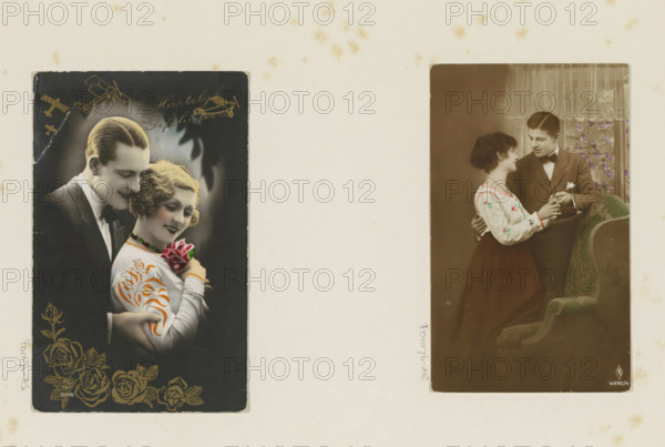 Volendam, Portrait of four children in Volendam traditional costume, album page, photograph, postcard, Part of Album with photos of railways in the Dutch East Indies and postcards., c. 1920 - c. 1940, photographer, pasteboard, paper, autotype, height 139 mm x width 87 mm, folk costume, regional costume, child, A faded scrapbook page shows two vintage photographic postcards mounted side by side against a cream background with small brown spots; the left postcard features a close portrait of a smiling couple with a man in a dark suit and slicked-back hair standing behind a woman with short wavy blonde hair who wears a light blouse with decorative patterns and holds a cluster of flowers, with gold floral designs along the bottom and small airplane illustrations near the top; the right postcard shows a different couple in a seated domestic scene with a man in a suit and bow tie holding the hands of a woman in a light blouse with embroidered details and a dark skirt, a patterned upholstered...