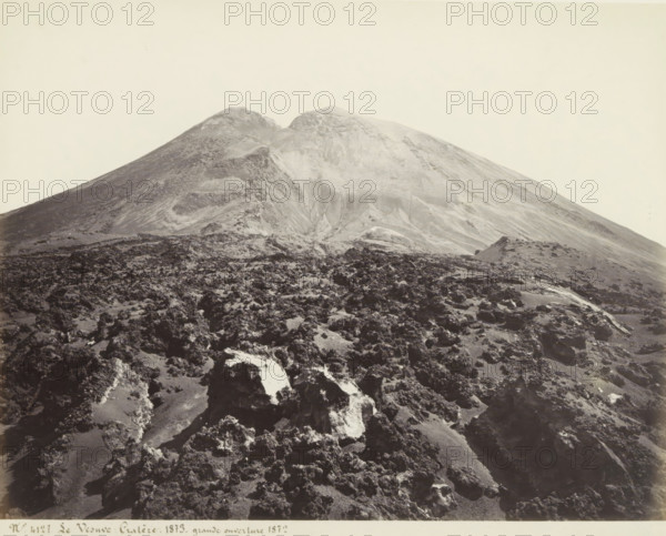 View of craters of Mount Vesuvius, Le Vesuve: Cratère, 1873, grande ouverture 1872, photograph, Part of Travel album with photos of sights in Naples and the surrounding area., negative number: '4127', Mount Vesuvius, in or after 1873 - c. 1875, photographer, paper, albumen print, height 199 mm x width 244 mm, volcano, cold lava, A wide, barren mountain rises from a rocky foreground, showing steep, smooth slopes with lighter and darker patches of exposed rock and ash, a rounded summit with two peaks, and a foreground covered in rough, jagged rocks and scattered lighter-colored stones under a pale, empty sky.