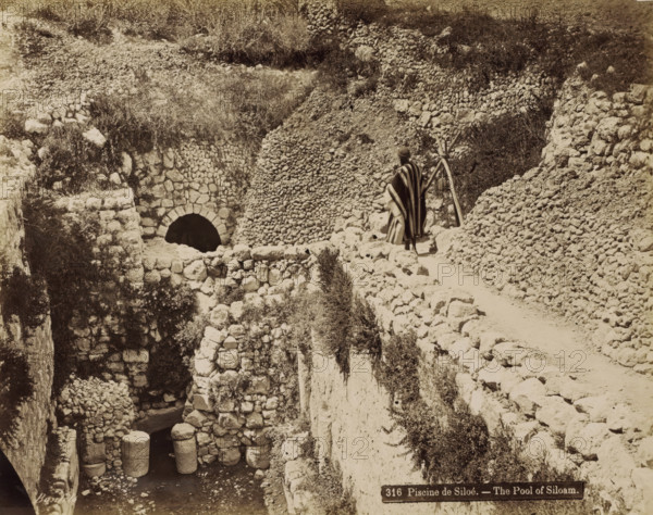 Pool of Siloam near Jerusalem, Piscine de Siloé. - The Pool of Siloam., photograph, Part of Travel Album with Photos of Jerusalem and Other Biblical Places., negative number: '316', photographer: Maison Bonfils, Jerusalem, c. 1867 - c. 1895, pasteboard, paper, albumen print, height 225 mm x width 283 mm, pond, pool, A sepia-toned scene of a rocky terrace and pathway carved into a hillside, showing rough stone walls and piled stones forming terraces and retaining structures, with an arched stone opening set into one wall above a lower chamber that contains large cylindrical stone columns partially submerged in water; vegetation and scrub grow among the stones and on the hillside, and a person wearing a striped cloak and head covering stands on the path facing away, near a simple wooden tripod or support.