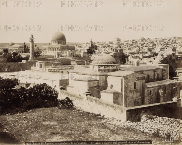 Eglise Ste-Anne et vue générale de Jérusalem.- St Anne's church and general view of Jerusalem., View of Jerusalem with St. Anne's Church in the foreground, photograph, Part of Travel album with photos of Jerusalem and other biblical places., negative number: '255', photographer: Maison Bonfils, Jerusalem, c. 1867 - c. 1895, pasteboard, paper, albumen print, height 226 mm x width 283 mm, prospect of city, town panorama, silhouette of city, church (exterior), St. Anne's Church (Jerusalem), A wide sepia-toned cityscape with a large domed building prominently near the center, several smaller domes and towers scattered across the view, a tall cylindrical minaret with a balcony rising in front of the domed complex, stone buildings with flat roofs and arched windows filling the foreground and stretching into the distance, low walls and terraces creating layered levels, patches of trees and vegetation interspersed among the structures, a rough rocky foreground leading up to the built area, and...