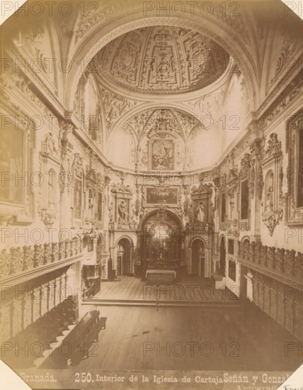 Interior of Real Monasterio de La Cartuja in Granada, Granada - Interior de la Iglesia de Cartuja, album page, photograph, This photo is part of an album., annotation: 'Granada - Cartuja', number: '250.', photographer: Señan y Gonzalez, c. 1885 - c. 1892-03-12, paper, albumen print, height 206 mm x width 161 mm, interior of church, Andalusia, Granada, A wide interior view of an ornate church nave with a high decorated dome and vaulted ceiling featuring intricate carved and painted panels, flanked by elaborately framed paintings and sculptural reliefs along both side walls, a central ornate altar area with decorative archways and religious imagery, rows of wooden pews on the left, carved balconies and balustrades lining the sides, patterned floor tiles leading toward the altar, and soft sepia-toned lighting across the architectural details.