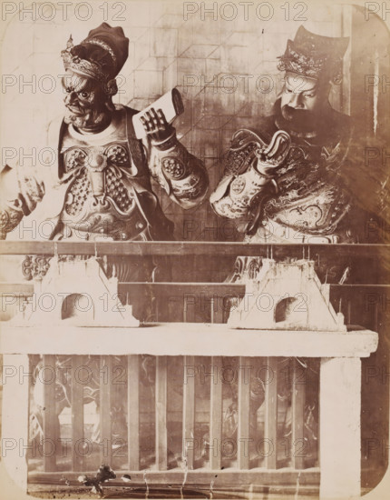 Two guardians, presumably from the Chenghuang Temple in Shanghai, photograph, annotation: 'Shanghai. Guardians of City Temple', Shanghai, 1850 - 1900, photographer, paper, pasteboard, albumen print, height 242 mm x width 205 mm, guardian, temple, shrine, traditional Chinese religions, Two carved figures in ornate armor and headdresses stand behind a wooden railing, one holding a rectangular object and the other with a raised hand; both have detailed facial features and expressive eyes, textured beards, and patterned breastplates with decorative motifs. The railing in front has vertical slats and a weathered horizontal top with triangular supports showing wear and chipped surfaces. The background shows a faint grid-like wall pattern and the overall image has a high-contrast, aged appearance with visible scratches and spots.