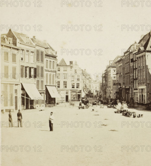 View of a square in Rotterdam, stereograph, inscription: '40', retailer's mark: 'BOEK EN PAPIERHANDEL, H. TEN HOET., NIJMEGEN', Rotterdam, 1857 - 1863, photographer, pasteboard, paper, albumen print, albumendruk, height 88 mm x width 179 mm, urban housing, square, circus, A wide street scene with rows of multi-story buildings lining both sides, many with awnings over ground-floor windows and shops, shuttered upper windows, and varied rooflines; people are scattered along the street and sidewalks, including a few standing figures in the foreground, small groups further back, and several seated figures near benches on the right; horse-drawn carts and a few vehicles are visible along the roadway, and there are small piles or marks on the open paved surface; the image has a high, empty sky above the buildings.