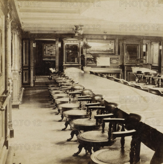 In a mail boat, Interior of the Koning Willem I, a mail boat of the Maatschappij Nederland, Collection E, Geographical sculpture gallery, collected by MJ Broekhuijsen, headmaster of a school in Amsterdam, stereograph, number: 'E.4.', number: '4.', inscription: 'Salon and dining room of the 'Koning Willem I' of the Maatschappij Nederland. Space for 50 persons. Daylight entering from above. Entrances to cabins on the left. In the background, open doors to the nursery. On the ceiling, in front of the bookcase on the left, an instrument with four blades rotating rapidly by means of electricity, which generate an airflow for ventilation.', Amsterdam, publisher: Merkelbach & Co., compiler (person in literature): Martien Johan Broekhuijsen, 1900 - 1902, photographer, compiler (person in literature), pasteboard, paper, albumen print, height 86 mm x width 176 mm, parts of ship's interior, A long dining room with a central table running toward the background, lined on one side with a row of roun...