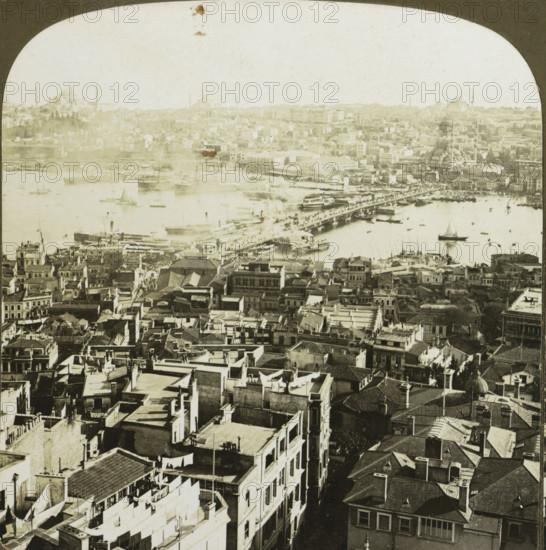 Galata Bridge over the Golden Horn in Istanbul, Constantinople, showing the Outer Bridge over the Golden Horn and Stamboul (the Turkish Quarter of the City) Turkey, stereograph, copyright notice: 'COPYRIGHT 1901 BY HC WHITE CO.', inscription: '... in, de Gouden Horn', number: '4302', inscription: 'J 3.', inscription: 'The 'PERFEC' STEREOGRAPH. (Trade Mark.), Patented April 14, 1903. Other Patents Pending.', Galatabrug, photographer: HC White Co., New York (city) (possibly), 1901, Istanbul, North America, paper, pasteboard, baryta paper, gelatin silver print, developing gelatin silver print, height 88 mm x width 177 mm, pontoon bridge, Golden Horn, Galata Bridge, A sepia-toned aerial view of a dense urban waterfront showing rows of closely packed buildings with flat and tiled roofs, narrow streets and alleys running between them, and rooftop details like chimneys, laundry lines, and small terraces; a busy harbor with various boats and sailboats scattered on the water, larger vessels doc...