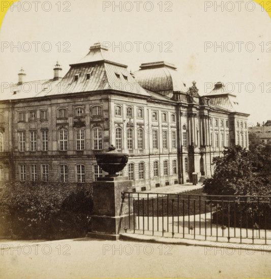 Dresde (Saxe), palais japonais, vu du jardin, Japanese palace in Dresden, Allemagne au stéréoscope, stereograph, inscription: 'J 60 cts', number: '241.', photographer: Charles Gaudin, Dresden, 1860 - 1870, Saxony, pasteboard, paper, albumen print, height 85 mm x width 174 mm, palace, Japanisches Palais, A sepia-toned photograph of a large classical building with a multi-level roof featuring steep metal slopes and decorative dormer windows, ornate cornices, and sculpted details above tall arched windows; a stone balustrade with a large ornamental urn on a pedestal sits in the foreground beside a metal railing and steps leading down, and trees and hedges frame the lower right and left edges of the scene.