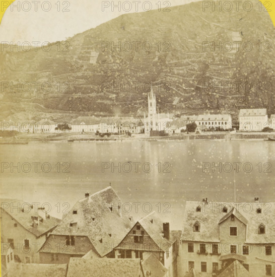 Saint-Goarshausen et le Rhin, vus de Saint-Goar, Sankt Goar and the Rhine, seen from Sankt Goarshausen, Germany, Allemagne, Bords du Rhin, stereograph, inscription: 'Déposé.', number: 'N. 483', photographer: Hippolyte Jouvin, Sankt Goarshausen, 1860 - 1870, Rhineland-Palatinate, pasteboard, paper, albumen print, height 86 mm x width 177 mm, river, city-view, and landscape with man-made constructions, Sankt Goar, A faded sepia photograph showing a riverside town with rows of buildings and steep tiled roofs in the foreground, a wide calm river in the middle reflecting light, and a distant shoreline with a cluster of larger buildings including a church with a tall steeple; behind them a steep terraced hillside rises, its textured slopes and horizontal lines visible under a pale sky.