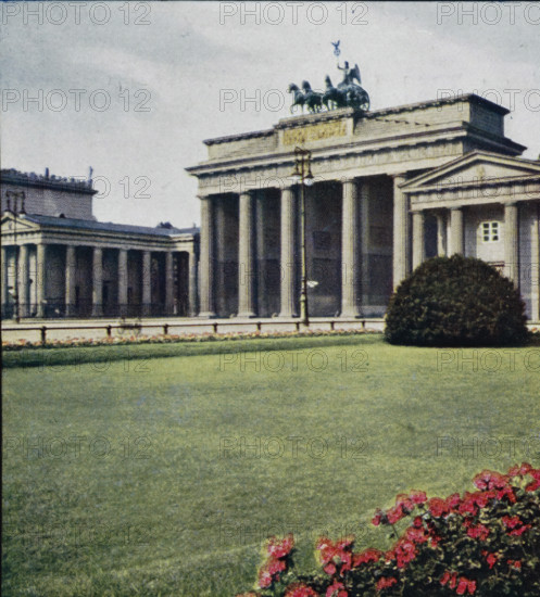 Brandenburg Gate in Berlin, Brandenburger Tor., Porte de Brandenburg., Arch of Brandenburg., Porta di Brandeburgo., Puerta de Brandemburgo, Berlin., Berlino, photomechanical print, stereograph, inscription: 'Warenzeichen, No. 142123', inscription: 'Series 7 Berlin I No. 55-60', inscription: 'DRGM, No. 437756', inscription: '4.', inscription: 'Westablschluss der Hauptstrasse 'Unter den, ', inscription: 'Chromoplast-Bild, No. 55', Berlin, cliché maker: Farbenphotographischen Gesellschaft, Stuttgart, publisher: Farbenphotographischen Gesellschaft, 1911 - 1919, Farbenphotographischen Gesellschaft, photographer, cliché maker, publisher, Baden-Württemberg, paper, pasteboard, three-color autotype, height 90 mm x width 180 mm, city gate, Brandenburg Gate, A classical stone building with tall columns and a triangular pediment is visible behind a large manicured lawn, with a sculptural group atop the roof showing figures and horses, a lamp post standing near the front of the columns, a rounded s...