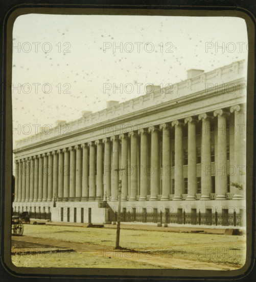 View of the Treasury Building in Washington DC, US Treasury, Washington DC, stereoscopic photograph, inscription: 'Entered according to Act of Congress, in the year 1856, by F. Langenheim, in the Clerk's Office of the District Court for the Eastern District of Pennsylvania.', inscription: 'F. Langenheim's Patent, Nov. 19, 1850.', photographer: Frederick Langenheim, 1856, North America, District of Columbia, inorganic material, glass, slide, hand coloring, height 85 mm x width 175 mm, treasurer, Treasury Building, A large neoclassical building fills the frame with a long colonnade of fluted columns topped by ornate capitals and an entablature with decorative molding and a balustrade along the roofline, a row of small roof structures visible above the balustrade; the façade shows a raised base with evenly spaced window openings and an iron fence running along the front, interrupted by a short flight of steps leading to a balcony with lamp fixtures; in front of the building a grassy area ...