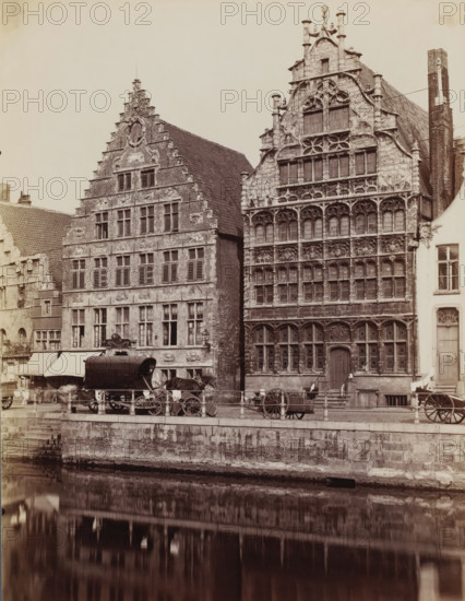 View of the Graslei in Ghent, Belgium, photograph, Ghent, 1851 - 1900, photographer, paper, albumen print, albumendruk, height 265 mm x width 204 mm, urban housing, canal, A row of tall historic stone buildings with ornate stepped and curved gables faces a canal, their façades featuring multiple rows of windows with shutters and decorative stonework; a covered carriage sits on the street in front of the buildings alongside horse-drawn wagons and wooden carts, with a low stone embankment and metal railing separating the street from the water, which reflects the buildings and vehicles below.