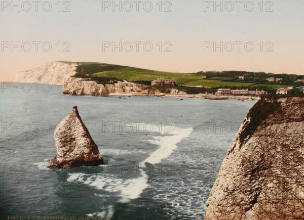 IOW Freshwater Stag Rock, View of Freshwater on the Isle of Wight, left the Stag Rock, photomechanical print, inscription: 'Knight's Library, 147 & 149, High St., and, Bank Buildings, Church St., Ventnor, IW', number: '10471.', Freshwater, cliché maker: Photochrom Zürich, Zürich (city), publisher: Photochrom Zürich, 1889 - c. 1920, Photochrom Zürich, photographer, cliché maker, publisher, Isle of Wight, paper, photochrom, height 165 mm x width 226 mm, coast, Stag Rock, A coastal scene showing a tall triangular rock rising from the sea in the foreground, a larger rocky cliff face on the right with patches of vegetation, calm blue-gray water with visible waves and white foamy trails leading toward the shore, pale chalk cliffs and green rolling fields along the distant coastline, several buildings including houses and larger structures near the shoreline, and a pale sky above.