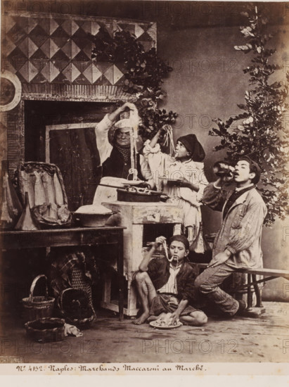 Scene with four people eating spaghetti in Naples, Italy, Marchands Maccaroni au Marché, Naples, photograph, number: '31.', number: 'No. 4152.', number: '12', inscription: 'p. 104 Giorgio Sommer', photographer: Giorgio Sommer, 1870, pasteboard, paper, albumen print, height 404 mm x width 307 mm, noodles, spaghetti, An indoor scene with a tiled wall section and foliage, showing a central older person holding long strands of pasta above a table, a young person beside them lifting strands toward their mouth while holding a plate, another young person seated on the floor eating from a plate, and a standing young person drinking from a bottle; surrounding them are baskets, containers, a cutting block or counter, hanging fish in a case, and various kitchenware.