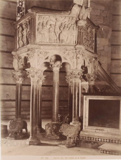 Pulpito del Battistero di N.Pisano, Pulpit of Nicola Pisano in the Baptistery in Pisa, Italy, Pisa, photograph, number: '1017.', after design by Nicola Pisano, 1851 - 1900, photographer, Tuscany, pasteboard, paper, albumen print, height 385 mm x width 308 mm, pulpit, ambo, chancel, Baptistery (Pisa), A stone pulpit with ornate carvings stands on a group of slender columns topped with carved capitals, each column rising from sculpted lion-shaped bases; the pulpit features rounded arches and relief panels depicting groups of robed human figures, with additional carved figures and decorative foliage around the arches and corner supports, and a carved eagle perched near a stairway that leads up to the pulpit, all set against a background of striped stone walls and tiled floor.