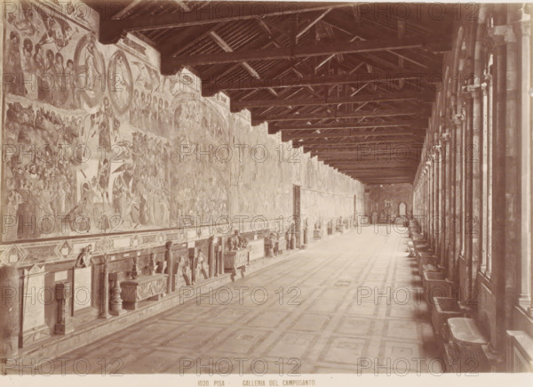 Galleria del Camposanto, Corridor in the Camposanto in Pisa, Italy, Pisa, photograph, number: '1020.', 1851 - 1900, photographer, Tuscany, pasteboard, paper, albumen print, height 309 mm x width 384 mm, wall-covering, gallery (spacious corridor), Piazza dei Miracoli, Camposanto (Piazza dei Miracoli), A long, vaulted interior space with a patterned floor and a high wooden beamed ceiling, one side lined with tall arches and columns and the opposite wall covered in large painted murals and decorative stone monuments mounted above a continuous bench, with sculpted reliefs and carved objects placed along the base and small windows or openings visible at the far end.