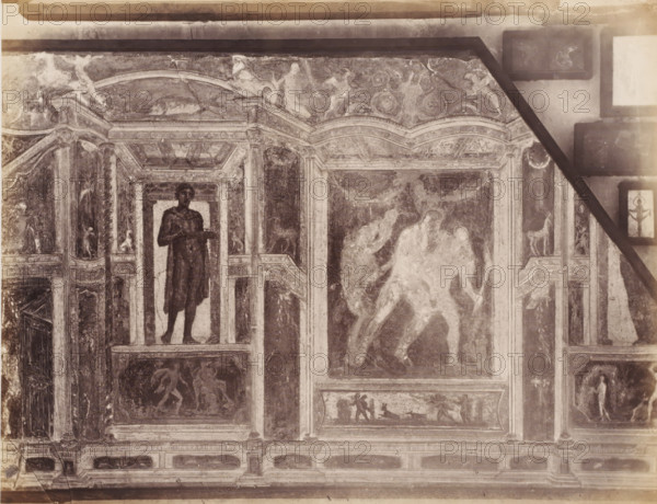 Fresco in a building in Pompeii, Italy, photograph, number: '73.', number: '11', inscription: 'Paroi Pompei', Pompeii, after painting by anonymous, 1851 - 1900, photographer, pasteboard, paper, albumen print, albumendruk, height 305 mm x width 403 mm, picture, painting, wall covering, A section of an ornate wall or ceiling paneling with framed painted scenes and decorative architectural elements, rendered in a faded monochrome tone. There are tall column-like vertical borders with carved capitals and bases separating rectangular and arched panels. One panel shows a standing male figure visible from head to feet, holding a shallow tray or platter. Another large central panel contains two overlapping human figures in motion, their forms blurred and lighter than the surrounding background. Smaller panels and friezes contain various human and animal figures in different poses, some appearing to walk or interact, and a panel shows a small animal resembling a four-legged creature on a ledge....