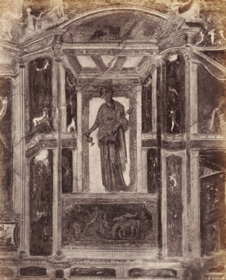 Photo reproduction of a fresco depicting a standing man in Pompeii, Italy, photograph, reproduction, number: '76.', inscription: 'Paroi Pompei', number: '11', Pompeii, after painting by anonymous, 1851 - 1900, photographer, pasteboard, paper, albumen print, height 403 mm x width 304 mm, picture, painting, wall-covering, A monochrome photograph of a painted wall panel showing a central tall niche containing a draped standing figure holding a long staff and a smaller object, flanked by architectural pilasters and decorative panels with classical motifs; above the niche is an ornate coffered arch with a small animal scene in the tympanum, and the surrounding panels contain faded figurative and ornamental paintings with worn textures, cracks, and areas of discoloration across the surface.