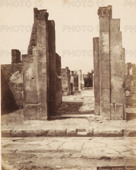 Remains of the Casa di Pansa in Pompeii, Italy, Pompei maison Pansa, photograph, number: '10', inscription: 'Pompei, maison Pansa Edile', Pompeii, 1851 - 1900, photographer, pasteboard, paper, albumen print, height 402 mm x width 304 mm, ruin of a dwelling, house, castle, Casa di Pansa, A sepia-toned photograph of a stone doorway flanked by two tall rectangular columns with carved capitals, leading into a courtyard framed by additional stone columns and ruins; the foreground shows a worn stone pavement and a low raised threshold, the walls and columns display weathered surfaces, blocks, and visible cracks, with textured masonry and scattered debris, and a narrow view through the doorway reveals more columns and fragments against a pale sky.