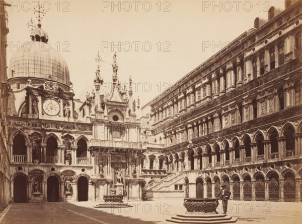 Cortile of Palazzo Ducale Venezia, Courtyard of the Doge's Palace in Venice, Italy, photograph, Venice, 1872, photographer, pasteboard, paper, albumen print, albumendruk, height 291 mm x width 390 mm, inner court of palace or 'hôtel', Doge's Palace, A sepia-toned view of an ornate courtyard featuring a large domed building with sculpted figures and a clock face, an elaborate façade with columns, arches, balustrades, and statues, a decorative fountain basin set on a stepped platform in the open plaza, and a man in dark clothing and a hat standing beside the fountain; the surrounding multi-level building has rows of arched openings and intricately carved stonework across its exterior.
