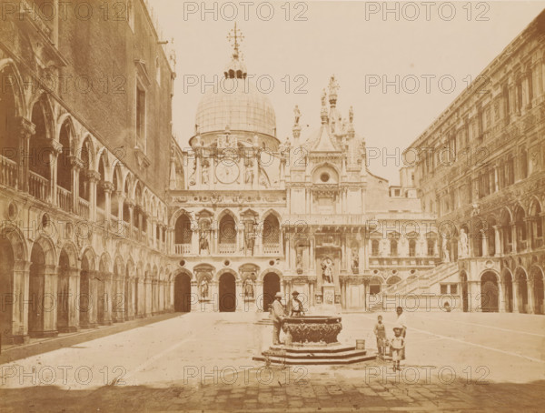Courtyard of the Doge's Palace in Venice, Italy, Cortile Palazzo Ducale, photograph, number: 'N 25', inscription: 'Venice', inscription: 'courtyard ducal palace', Venice, 1851 - 1900, photographer, pasteboard, paper, albumen print, height 310 mm x width 400 mm, ornamental fountain, inner court of palace or 'hôtel', Doge's Palace, A wide courtyard framed by ornate stone arcades on both sides with multiple arched openings and columns, a central ornate fountain with sculpted basin where two men stand nearby, a large domed building with decorative statues and carved facades in the background, several figures including children walking or standing near the fountain and along the open paving, and a grand staircase and additional sculptural details on the building to the right.