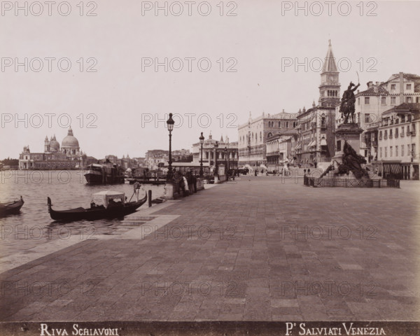 View of the Riva degli Schiavoni in Venice, Riva Schiavoni, photograph, inscription: 'Venetie', photographer: Paolo Salviati, Venice, 1860 - 1870, pasteboard, paper, albumen print, albumendruk, height 197 mm x width 250 mm, height 275 mm x width 364 mm, canals, waters (in city), quay, Riva degli Schiavoni, A wide paved waterfront promenade runs from the foreground to the midground with ornate lamp posts lining the edge near the water, where several moored gondolas and small boats sit along a stone quay, one gondolier standing in a boat near the nearest edge; people stand and walk along the quay and near the boats. On the right, a multi-figure equestrian statue on a raised pedestal is surrounded by a low fence in front of a row of multistory buildings with shuttered windows and awnings. Further back on the right, a tall bell tower rises above ornate palatial buildings with arched windows and decorative facades. Across the water on the left, a domed church and adjacent classical building...