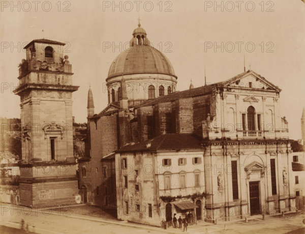 Exterior of the San Giorgio in Braida in Verona, Italy, photograph, inscription: 'Verona.', number: '13', Verona, 1851 - 1900, photographer, pasteboard, paper, albumen print, albumendruk, height 303 mm x width 405 mm, church (exterior), San Giorgio in Braida, A sepia-toned photograph showing a large classical church complex with a prominent domed roof and adjacent bell tower, stone façades with decorative cornices and pilasters, arched windows and sculpted niches, and a tiled sloping roof section with visible wear; the bell tower has an open belfry and ornamental spheres at its corners, while the church façade features a triangular pediment and a large arched window above a main entrance with heavy doors; several small rectangular windows and weathered brick and plaster walls are visible on the adjoining buildings, and a small group of people stands near a doorway under a simple awning at street level.