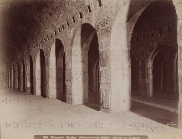 Solomon's Stables, Solomonic Ställe, Ecuries de Salomon, Solomon's stables in Jerusalem, photograph, number: '384', Jerusalem, 1860 - 1900, photographer, paper, albumen print, height 211 mm x width 277 mm, ritual practices, Islam, Mohammedanism, A long covered stone corridor with a series of tall rounded arches supported by thick rectangular pillars receding into the distance, a vaulted ceiling with small rectangular openings near its upper edge, rough textured stone surfaces on the arches and walls, deep shadowed recesses visible through the arches, a sandy floor with scattered small debris, and light creating bright areas on some pillars and the floor.