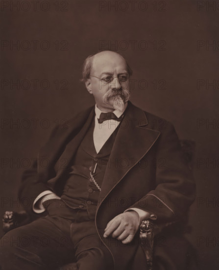 Portrait of Charles-Philippe Robin, Charles-Philippe Robin, page, photomechanical print, inscription: 'Galerie Contemporaine, 126, boul. Magenta. - Paris. (Né a Jasseron (Ain), le 4 juin 1821)', photographer: Ferdinand Mulnier, cliché maker: Goupil & Cie., c. 1874 - c. 1879, paper, Woodburytype, Woodburytypie, height 229 mm x width 186 mm, Person, historical persons, adult man, A seated older man wearing round eyeglasses and a suit with a waistcoat and bow tie is shown from the torso up against a plain dark background, his hair is thinning and he has a large mustache and pointed goatee, one hand rests on an ornately carved armrest while the other is tucked near his waist, and a pocket watch chain is visible across his vest.