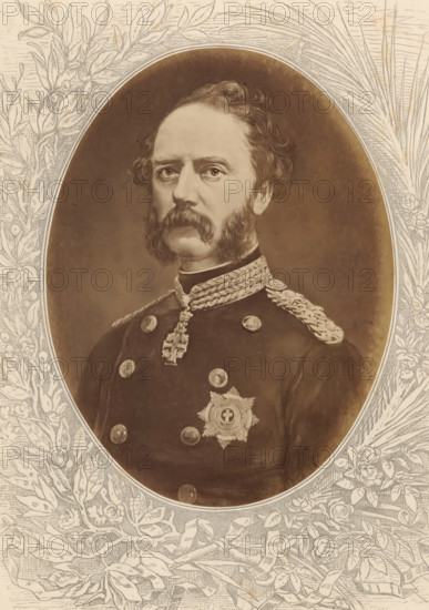 Photo reproduction of a painted portrait of Christian IX, King of Denmark, Christian IX, König von Dänemark, photograph, reproduction, page, after painting by anonymous, c. 1875 - in or before 1880, photographer, paper, albumen print, albumendruk, height 189 mm x width 143 mm, Photo on unnumbered page., Person, historical persons, king, An oval portrait of a man with wavy hair and prominent sideburns and mustache fills the center, showing his head and upper torso in a dark military uniform with decorative braided epaulettes and a high collar; the uniform bears round buttons and a star-shaped medal with a circular center, and a cross-shaped pendant hangs from a braided cord at his throat. The background inside the oval is a smooth, softly shaded surface, and the oval is set within a rectangular border decorated with detailed botanical engravings of leaves, branches, and flowers that frame the portrait.
