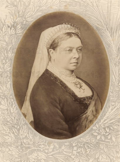 Photo reproduction of a painted portrait of Victoria, Queen of Great Britain and Ireland, Empress of India, Victoria, Königin von Grossbritanien und Irland, Kaiserin von Indien, photograph, reproduction, page, after painting by anonymous, c. 1875 - in or before 1880, photographer, paper, albumen print, height 188 mm x width 143 mm, Photo on unnumbered page., Person, historical persons - BB - woman, queen, A sepia-toned oval portrait of a woman shown from the chest upward wearing a dark dress with a low neckline and a light veil draped over the back of her head, a jeweled crown or tiara at her hairline, layered pearl necklaces and a pendant brooch at her chest, small drop earrings, and a composed facial expression with eyes looking slightly to the side; the oval image is set against a textured background and surrounded by an ornate floral and leafy engraved border.