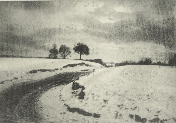 Landscape with country road in winter, Une route de campaign en hiver, photomechanical print, photographer: Charles Job, cliché maker: Fillon & Heuse, printer (person): Charles Wittmann, Paris, c. 1891 - in or before 1896, printer (person), paper, photoaquatint, height 133 mm x width 191 mm, road, path, low hill country, winter landscape, landscape symbolizing winter (the four seasons of the year), A grainy black and white landscape showing a snow-covered field with a curving snow-lined path or ditch leading toward the middle distance, dark patches of exposed ground along its edges, and a small group of bare trees on the horizon beneath a wide, cloudy sky.