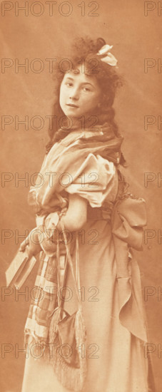 Lecture interrompue, Portrait of an unknown girl with a book, photomechanical print, photographer: Maurice Bucquet, cliché maker: Fillon & Heuse, printer (person): Charles Wittmann, Paris, c. 1891 - in or before 1896, printer (person), paper, photoaquatint, height 238 mm x width 100 mm, historical persons - BB - woman, book, A full-length portrait of a young girl turned slightly to the side, with curly hair adorned with a ribbon and a small flower, wearing a dress with puffed sleeves and a large bow at the back, a shawl draped around her shoulders, a small fringed bag hanging at her side, and holding a couple of books in one hand, all shown against a plain backdrop.