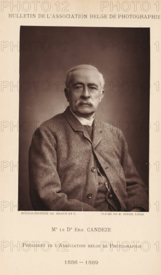 Mr. le Dr. Ern. Candeze. Président de l'Association Belge de Photographie (1886-1889), Portrait of Ernest Candèze, president of the Association belge de Photographie, page, photomechanical print, photographer: Léonard Hubert Zeyen, cliché maker: Adolphe Braun & Cie., printer (person): Adolphe Braun & Cie., Dornach, 1886 - 1889, Léonard Hubert Zeyen, Adolphe Braun & Cie., photographer, cliché maker, printer (person), Mulhouse, paper, Woodburytype, height 144 mm x width 102 mm, Print on unnumbered page., Person, Ernest Candèze, historical persons, adult man, chairman, A sepia-toned portrait of an older man seated and facing forward, shown from the waist up against a plain dark background, with short light hair, a full mustache, and rimless glasses; he wears a textured jacket over a buttoned waistcoat and a high-collared shirt, and his hands rest in his lap with a faint crease or line visible on the lower part of the photograph; the portrait is centered within a wider lighter-toned page t...