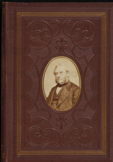 Portrait of Johannes Petrus Hasebroek, photograph, page, c. 1863 - in or before 1868, photographer, paper, albumen print, height 68 mm x width 48 mm, Photo on front cover., Person, Johannes Petrus Hasebroek, historical persons, A textured brown cover with an embossed decorative pattern and concentric rectangular borders in a lighter tone, featuring an oval inset with a sepia portrait of a bearded man wearing a jacket and bow tie, the portrait surrounded by a thin gilded rim.