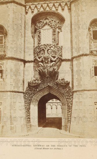 Entrance gate on the terrace of the Palácio da Pena in Sintra, Moresco-gothic archway on the terrace of the Pena (Colossal Monster over Archway), photograph, page, Sintra, c. 1865 - in or before 1870, photographer, paper, albumen print, height 197 mm x width 142 mm, Photo on third unnumbered page after page 20., gate, entrance, palace, Palácio da Pena, A sepia-toned photograph of a decorated stone archway set into an ornate façade, with a pointed arch passageway leading inward to a view of arched openings beyond; above the arch is a sculptural relief of a grotesque human-like face with muscular arms and bent legs emerging from a shell-like base, surrounded by carved foliage and wave-like ornamental forms; flanking the central bay are textured stone towers and patterned wall surfaces with framed windows and decorative stonework, and the whole composition is richly detailed with relief carvings and ornamental borders.