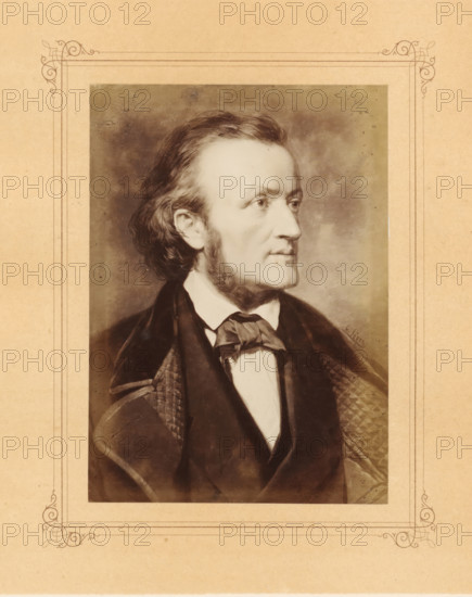 Photo reproduction of a painted portrait of Richard Wagner by Carl Jaeger, photograph, reproduction, page, after painting by Carl Jaeger, in or after 1870 - in or before 1872, photographer, paper, albumen print, albumendruk, height 150 mm x width 107 mm, Person, Richard Wagner, picture, painting, portrait of composer, A sepia-toned portrait of a man shown in profile facing right, with wavy hair brushed back and sideburns, wearing a dark coat over a white shirt and a tied neckcloth, set against a mottled background and surrounded by a decorative rectangular border on aged paper.