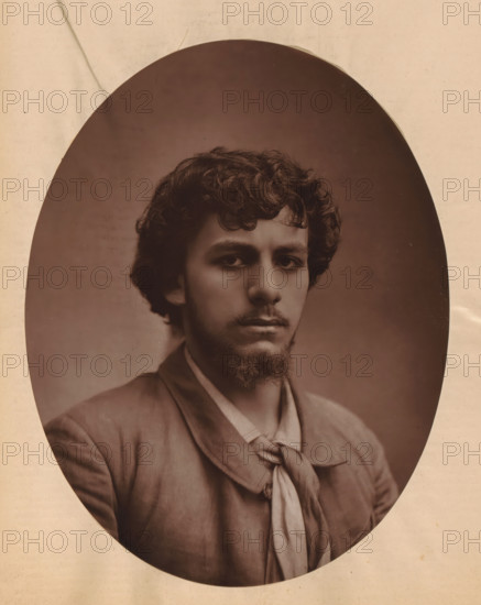 Portrait of Albert Lambert, page, photomechanical print, photographer: Félix Nadar, cliché maker: Lemercier, c. 1880 - c. 1885, paper, Woodburytype, Woodburytypepie, height 243 mm x width 189 mm, Person, Albert Lambert, historical persons, portrait of actor, actress, A sepia oval portrait shows a young man with curly dark hair and a short beard and mustache, his face turned slightly toward the camera with a neutral expression, wearing a jacket over a shirt and a loosely knotted scarf around his neck, set against a plain darker background and framed by a lighter paper border with subtle creases and spots.