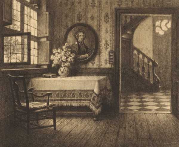 Interior with portrait, table and view of a corridor, print, number: '22', printmaker: René Janssens (signed by artist), 1880 - 1936, paper, lithography, height 430 mm x width 452 mm, interior of the house, anonymous historical person depicted, flowers in a vase, A softly lit interior scene rendered in warm sepia tones shows a window with multiple panes and shutters on the left, a wooden chair with armrests in the foreground, and a table covered by a cloth and a patterned throw against the wall. On the table sits a vase filled with clustered flowers and a book. Above the table hangs an oval framed portrait of a person. To the right an open doorway reveals a curved staircase with a carved banister and a checkered floor visible beyond. The walls display a subtle patterned wallpaper, and wooden floorboards run across the room.