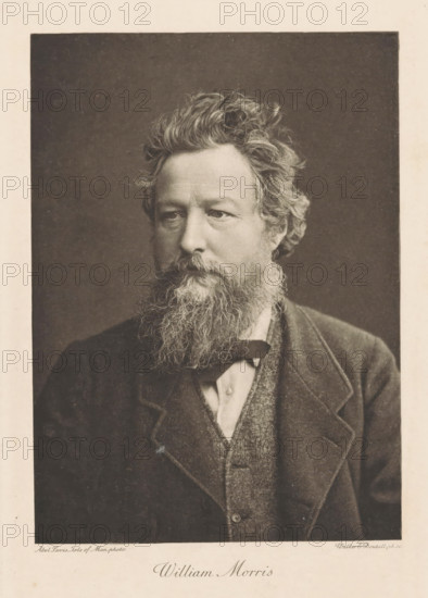 Portrait of William Morris, William Morris, print, photograph, printmaker: Walker & Boutall, London, photographer: Abel Lewis, Isle of Man, 1887 - 1900, paper, photoaquatint, heliogravure, height 181 mm x width 121 mm, Person, portrait, self-portrait of artist, A sepia-toned portrait of a middle-aged man shown from the chest up, facing slightly to his left, with a full, curly beard and mustache and wavy hair swept back; he wears a dark jacket over a textured vest and a light-colored shirt with a narrow bow at the collar, and the background behind him is plain and dark.