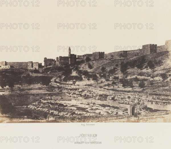 Basin of Birket-es-Soultan outside the Old City Wall of Jerusalem, Jérusalem. Birket-es-Soultan, photograph, page, photographer: Auguste Salzmann, Jerusalem, printer (person): Louis-Désiré Blanquart-Evrard, Lille, publisher: Gide et J. Baudry, Paris, 1854 - 1856, printer (person), pasteboard, paper, salted paper print, height 155 mm x width 218 mm, Photo on unnumbered page., city-view in general, 'veduta', pond, pool, Birket-es-Soultan, A wide sepia-toned landscape showing a stone city wall and fortress along a ridge with a tall narrow tower rising above the ramparts, the foreground featuring terraced, rocky hillside with scattered dark shrubs and a winding path, and an arched stone opening visible near the lower edge.