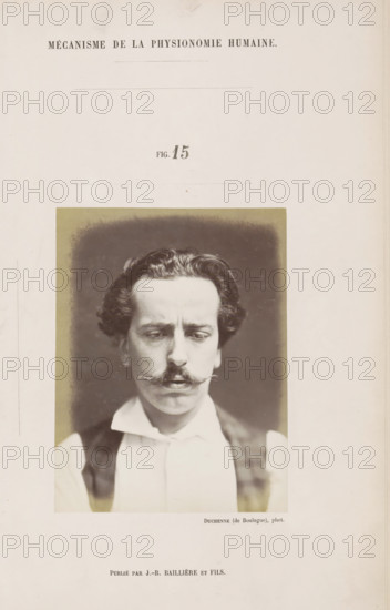Portrait of a subject: 'un jeune homme', photograph, page, Unnumbered page with photo 15 from Mécanisme de la physionomie humaine ou analyze électro-physiologique de l'expression des passions (Atlas)., photographer: Guillaume Benjamin Amand Duchenne, France, publisher: JB Baillière et Fils, Paris, c. 1860 - in or before 1862, Guillaume Benjamin Amand Duchenne, JB Baillière et Fils, photographer, publisher, paper, albumen print, albumendruk, height 120 mm x width 91 mm, adult man, experiment, test, science and technology, face, morphology of facial expression, physiology and anatomy, physiognomy, nervous system, neurology, A vertically oriented page with a sepia-toned photographic portrait centered in the lower half, showing a man from the shoulders up against a dark blurred background; he has wavy dark hair, a pronounced mustache, downcast eyes, and a furrowed brow, wearing a light-colored shirt with a high collar and a dark vest, with the portrait framed by a lighter rectangular borde...