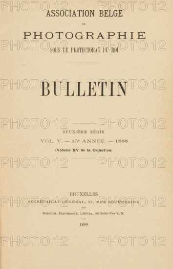 Association belge de photographie bulletin 15e année: 1888, book, printer (person): A. Lefèvre, Brussels, printer (person), pasteboard, biological material, paper, blotting paper, leather, marbled paper, baryta paper, letterpress printing, agate marbled paper, collotype, Woodburytype, heliotype, chlorobromide development paper print, autotype, height 243 mm x width 172 mm x thickness 49 mm, A vertically oriented aged paper page with a centered large bold heading near the top, additional smaller lines of printed headings and decorative lines arranged vertically down the page, a wide blank margin surrounding the printed area, and a visible horizontal fold across the lower third of the page.