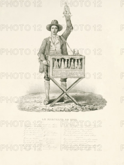 Le Marchand de Rois, The Kingsman, 1831, cartoon, print, Caricature of the negotiations regarding the selection of a Belgian king, February 1831. A masquerade artist with a barrel organ and eight dolls dressed as monarchs. The organist holds a little king up in his hand. With a French song in four verses at the bottom., printmaker, Belgium, paper, lithography, height 369 mm x width 282 mm, one person playing an instrument - CC - out of doors, street-organ, 'pierement' - CC - out of doors, Selection of a King in Belgium, Period, A young man stands on a cobblestone surface wearing a brimmed hat, a jacket over a collared shirt and vest, breeches, and high stockings with shoes; he holds a small ornate box on a folding stand at his waist and raises one arm above his head holding a small figurine while another figurine and a miniature figure sit atop the box, the front panel of which displays a row of carved small figures behind a decorative trim.